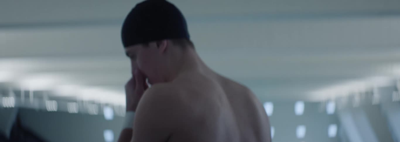 Male swimmer walking in a natatorium turns around then stands still