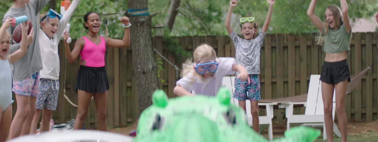 Children are cheering for a girl as she runs in the yard