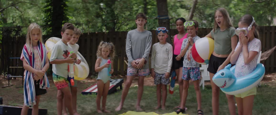 Children are shocked at the girl laying on the slip and slide