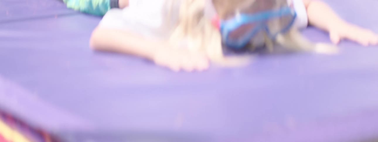 The video captures children playing outdoors on a sunny day with one child wearing blue swimming goggles on her head and another boy in the background raising his arms in excitement the clip also shows a girl holding a water gun and smiling suggesting