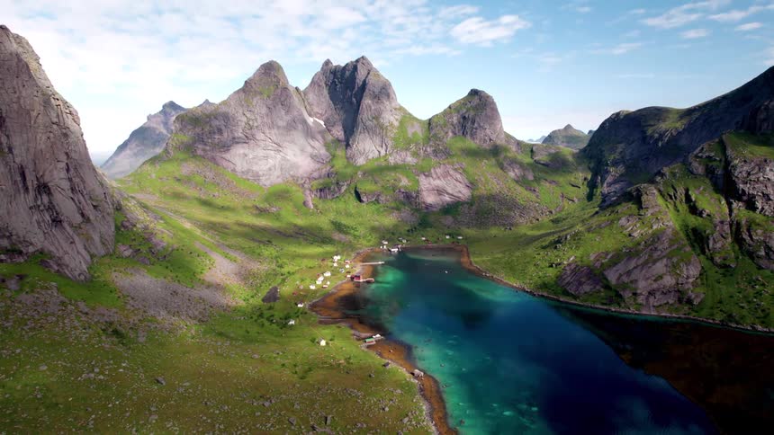 Town sits on the shore of a darkreflective lake surrounded by mountains on a cloudy day