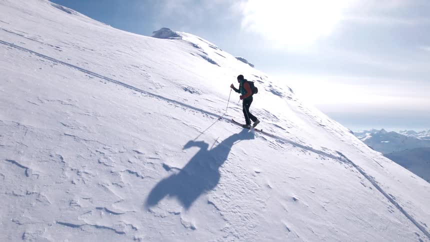 The man is hiking up the steep hill full of snow