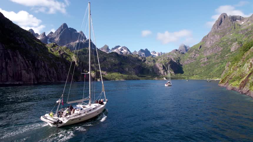 Small boats traveling through an area surrounded by mountains