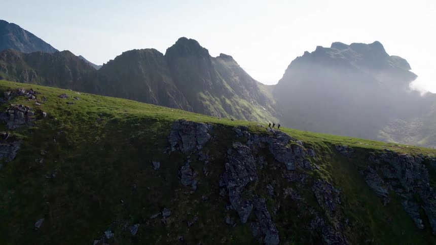 Three people on a horizon hiking on a mountain with cliffs