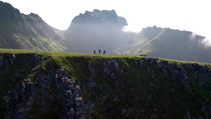 Three people walking along a mountain trail with cliffs