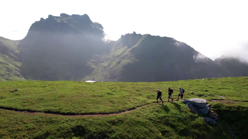 Three people hiking on a trail on the green mountain