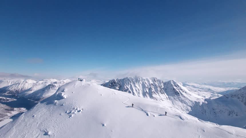 Distant people climbing a snowy mountain