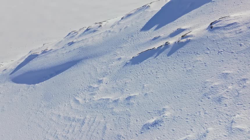 Patches of stone show through the snow covered terrain of a mountain on a winter day