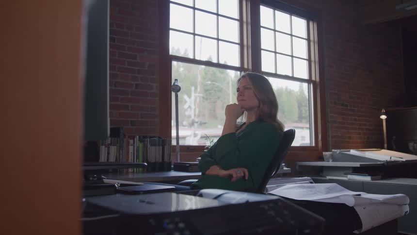 Architect sitting and looking at a computer thinking