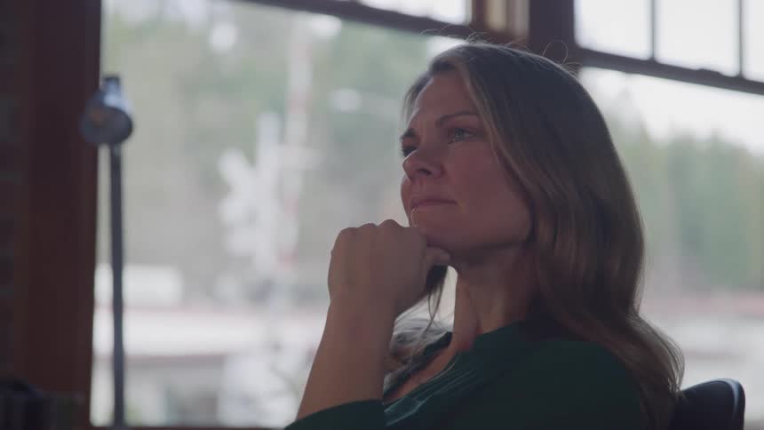 Woman in an indoor space concentrating with her hand on her chin
