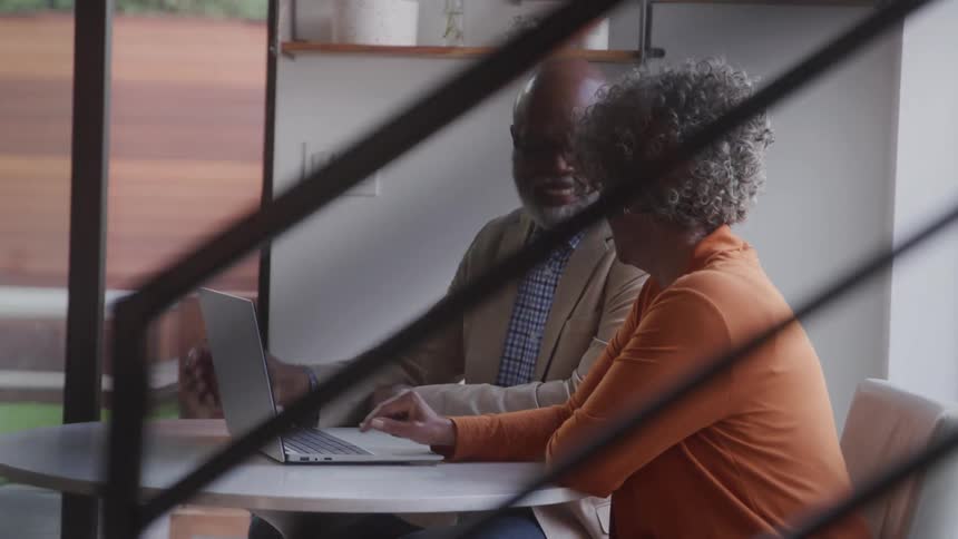 Grandma and grandpa are laughing while watching something on a laptop