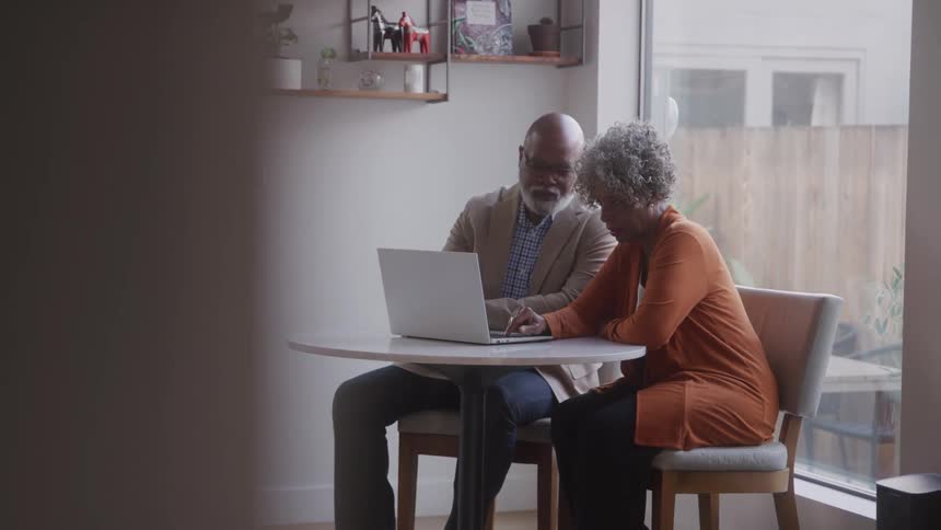 A couple are talking and using a laptop together