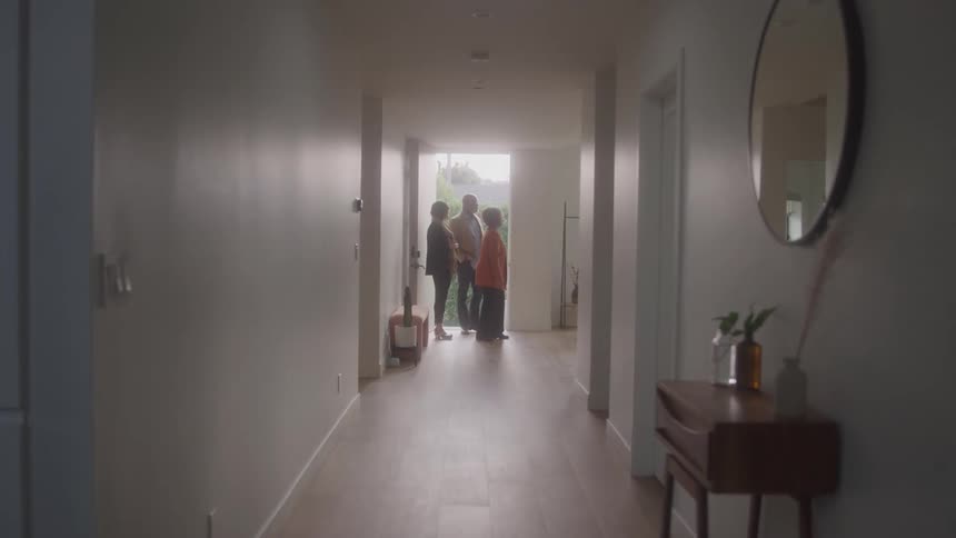 An elderly couple walks into a building with a female agent to inspect the property all of them smiling and laughing together