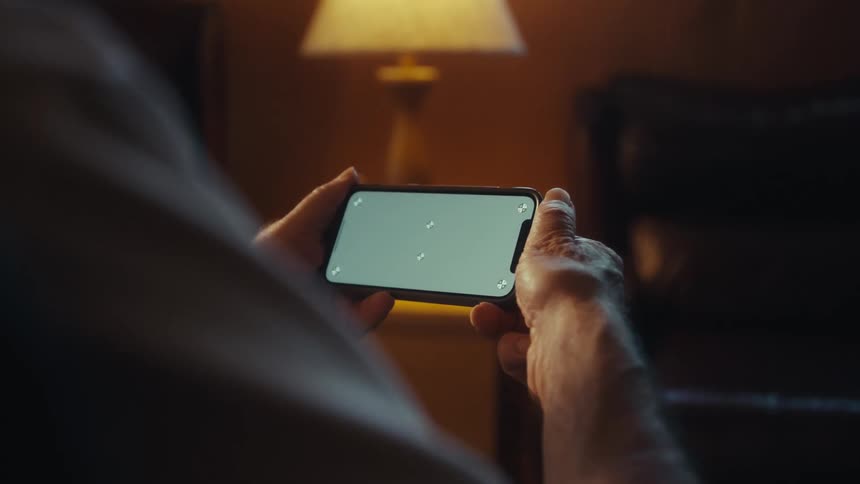 Elderly man sitting interacting with a smartphone