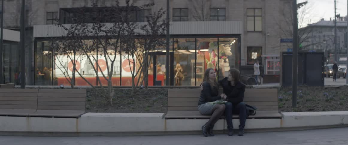 A man and woman cuddle on a city bench