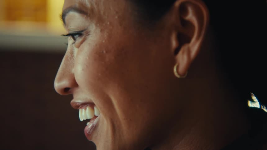 A woman typing on a laptop and smiling happily