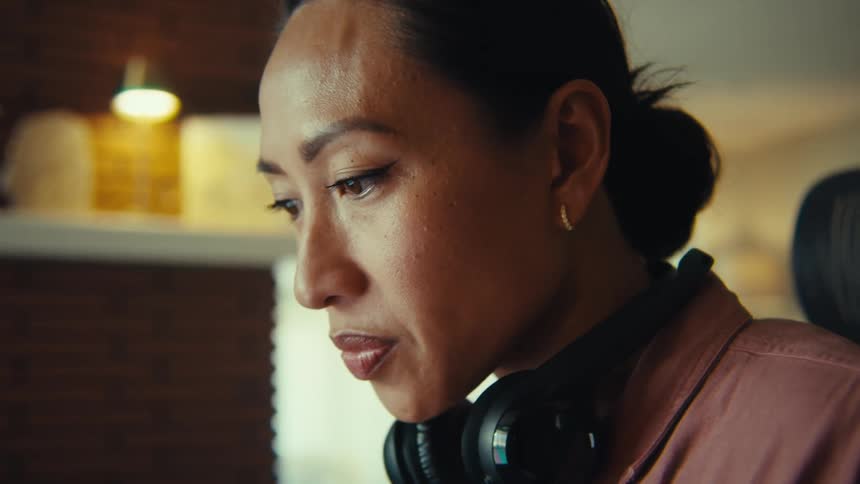 A woman sits in a chair with headphones around her neck