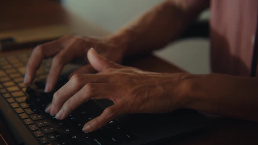 This video provides a closeup of a persons hands typing on a black laptop keyboard with visible light reflecting off the keys the angle and focus emphasize the act of typing suggesting work or communication