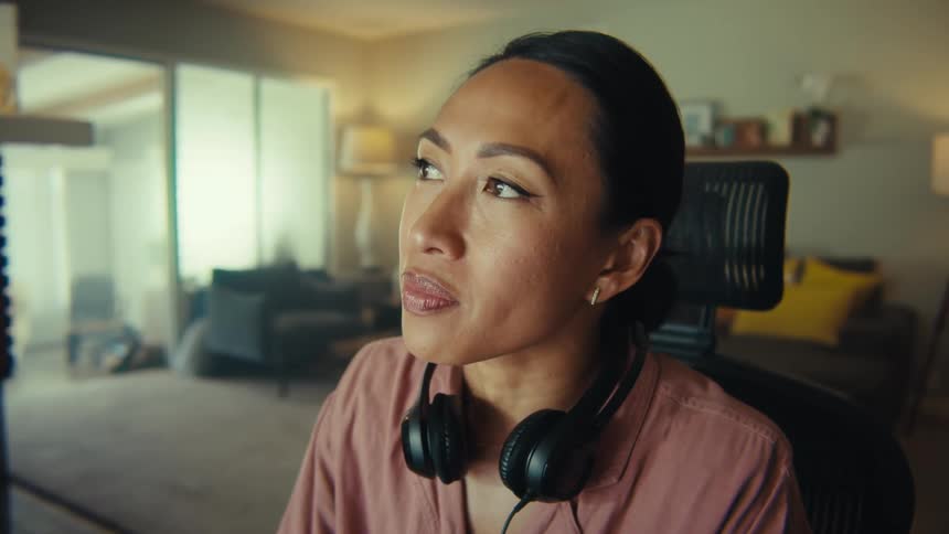 Woman sitting typing while wearing headphones around her neck