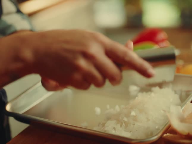 Woman placing chopped onion on a metal surface