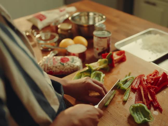The woman is cutting vegetables in the kitchen