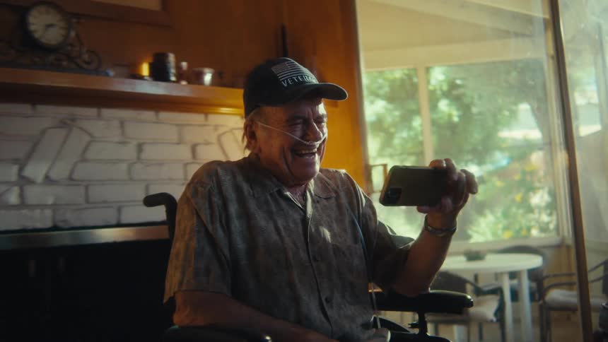 A man happily watches something on his phone