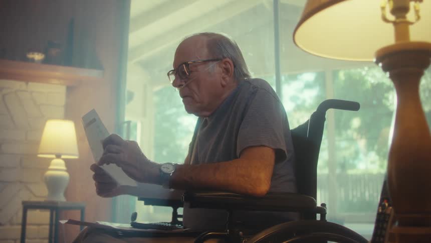 Elderly man sitting indoors reading a document