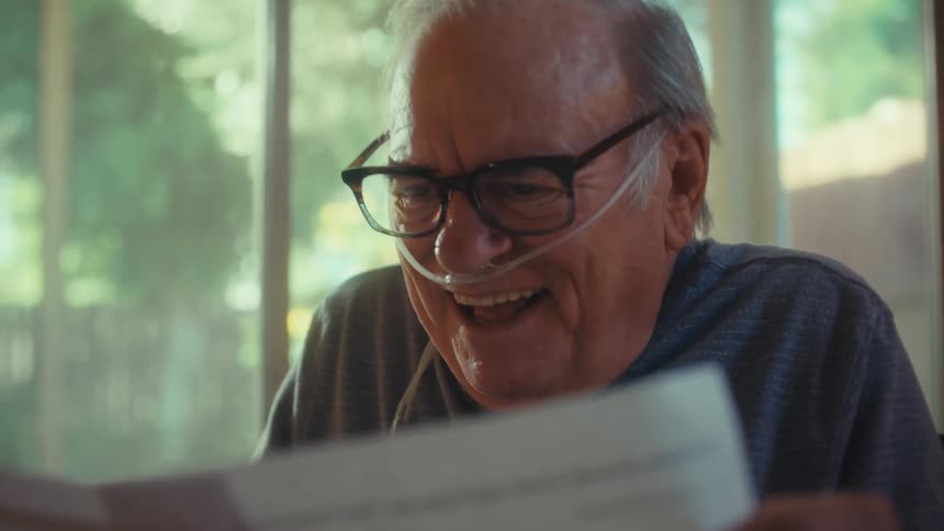 Elderly man with happy expression reading a document