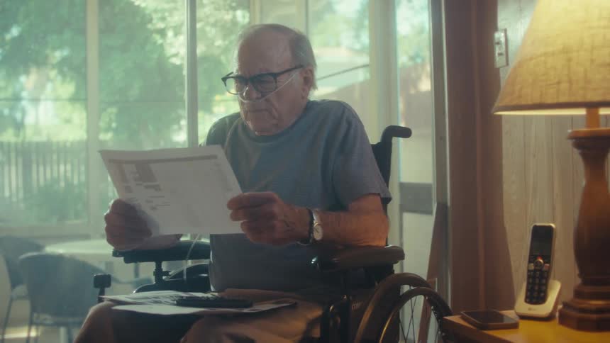 Elderly man in a wheelchair reading documents