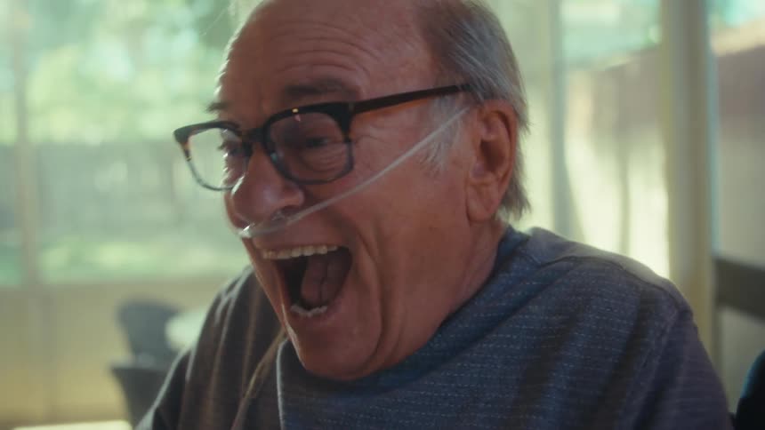 Elderly man with thin oxygen tube in his nose looking extremely happy reading a document