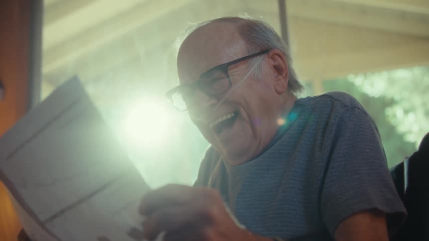 Elderly man with a happy expression reading documents in an indoor space
