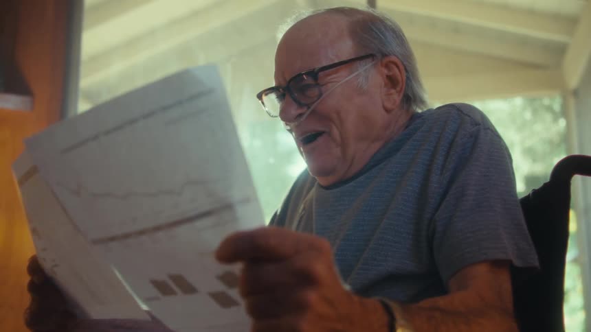 Elderly man with happy expression sitting reading documents