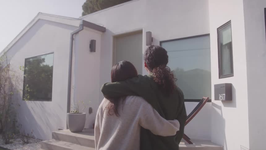 Couple hugging in front of a house