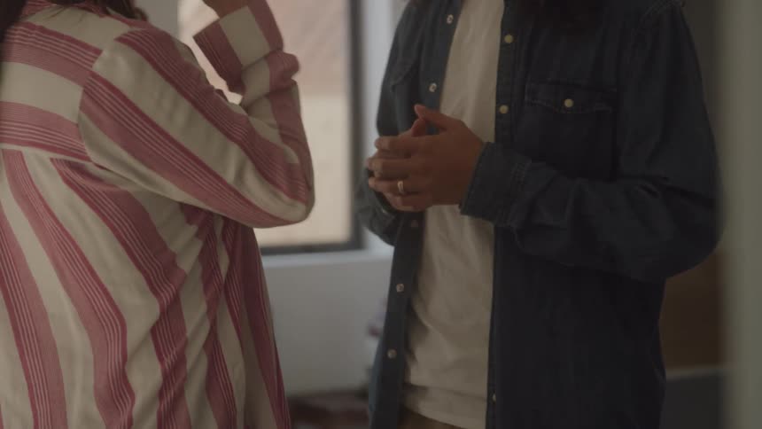 Two people talk indoors as one gestures
