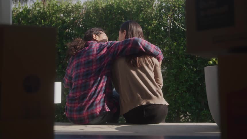 Couple hugs warmly on bench laughing together