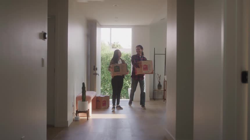 Couple walking into empty house with moving boxes
