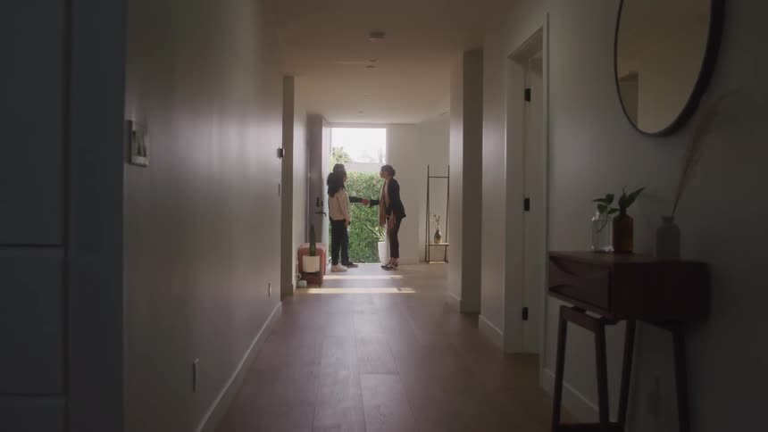 A group of people greets each other at a house entrance during a tour