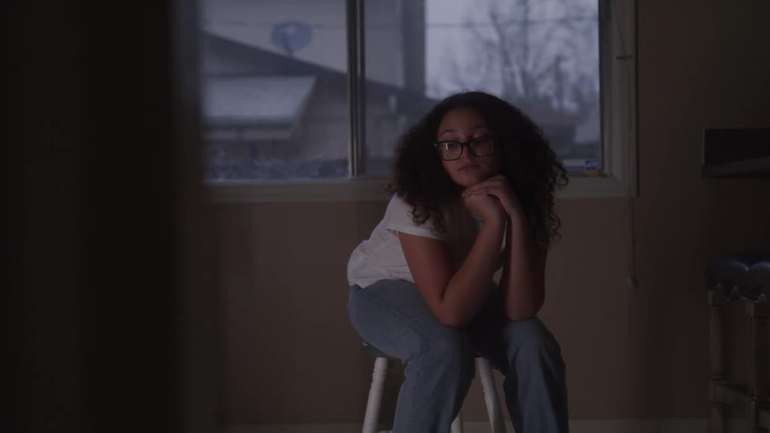 Woman with curly hair with her hand on her chin looking discouraged