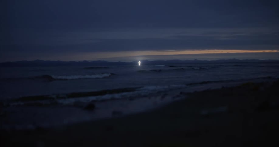 A beach view at night shows ocean waves crashing against the shore
