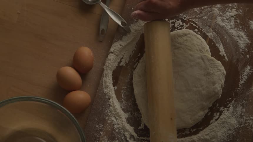 A wook is using a rolling pin on dough