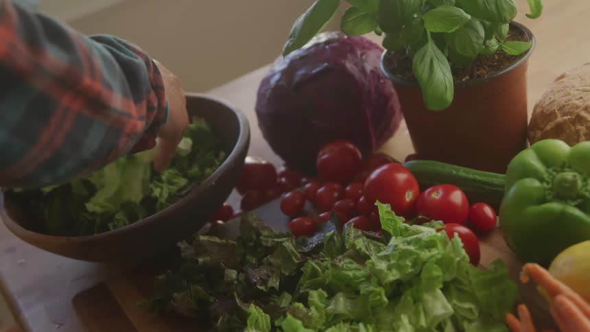 Pair of hands putting chopped lettuce into a bowl