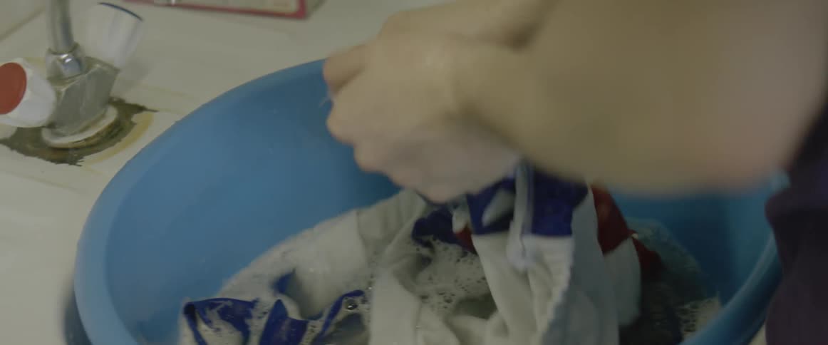 A man washes clothes in a tub