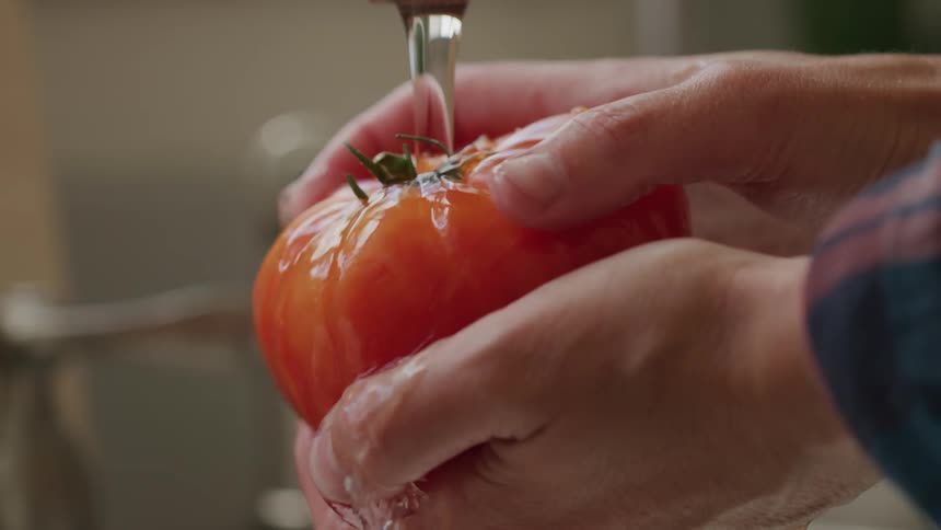 A person washes a tomato