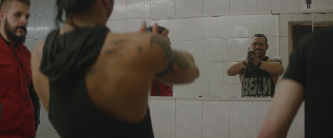 A man exercises with a weight while looking in a mirror