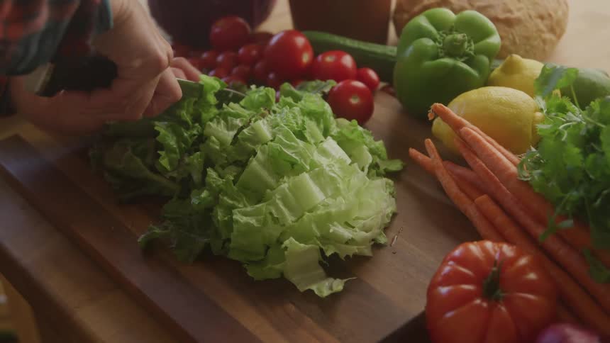 A person cuts up a head of lettuce