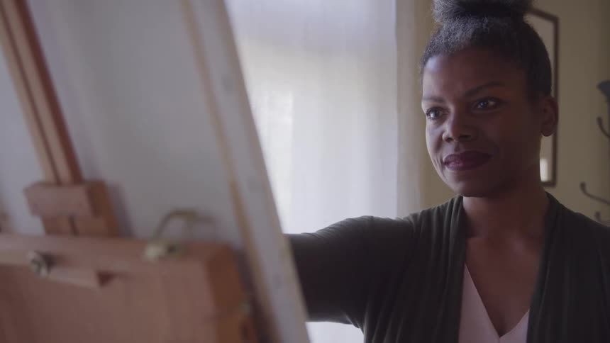 Woman in an indoor space painting a canvas