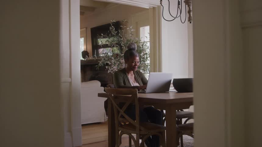 A woman working on the laptop while sitting at the dining room table