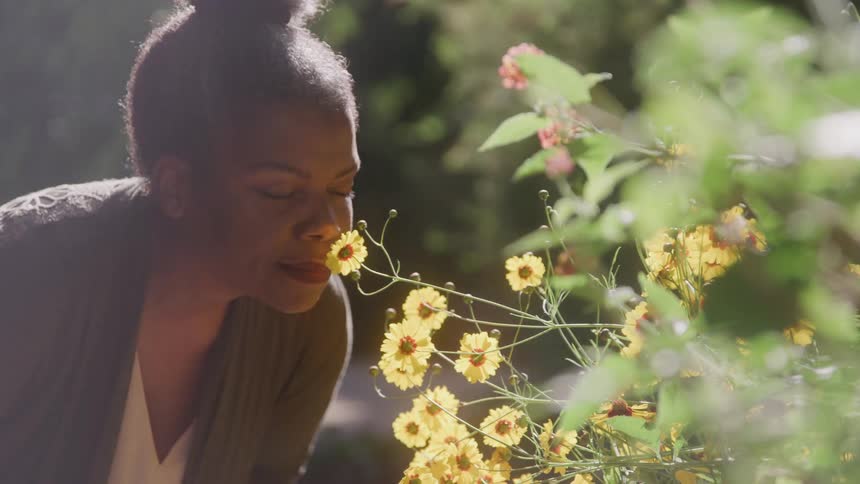 Woman outdoors smelling a flower
