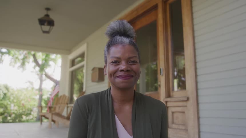 Smiling face of a black woman sitting at the front door of a house at dawn