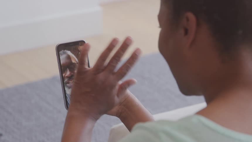 Woman waving goodbye while on a video call with a man